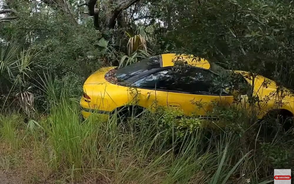 A bright yellow Dodge Stealth in the bush